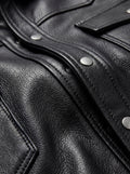 Macro shot of grained black leather texture and silver snap button details on western shirt. Maverick Easton.