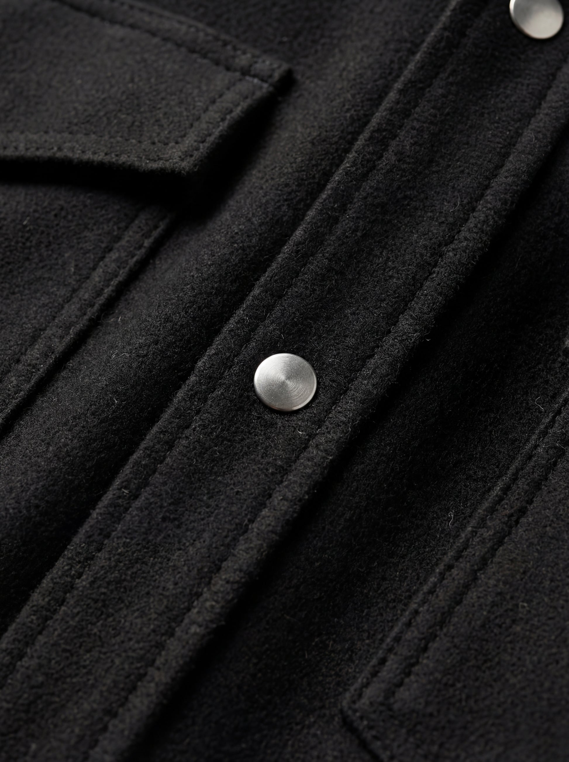 Macro shot of soft black suede texture and silver snap button detail on western shirt. The Cole by Maverick Jacket.