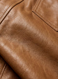 Macro shot of grained tan leather texture and silver snap button detail on western shirt. The Colton by Maverick Jacket.