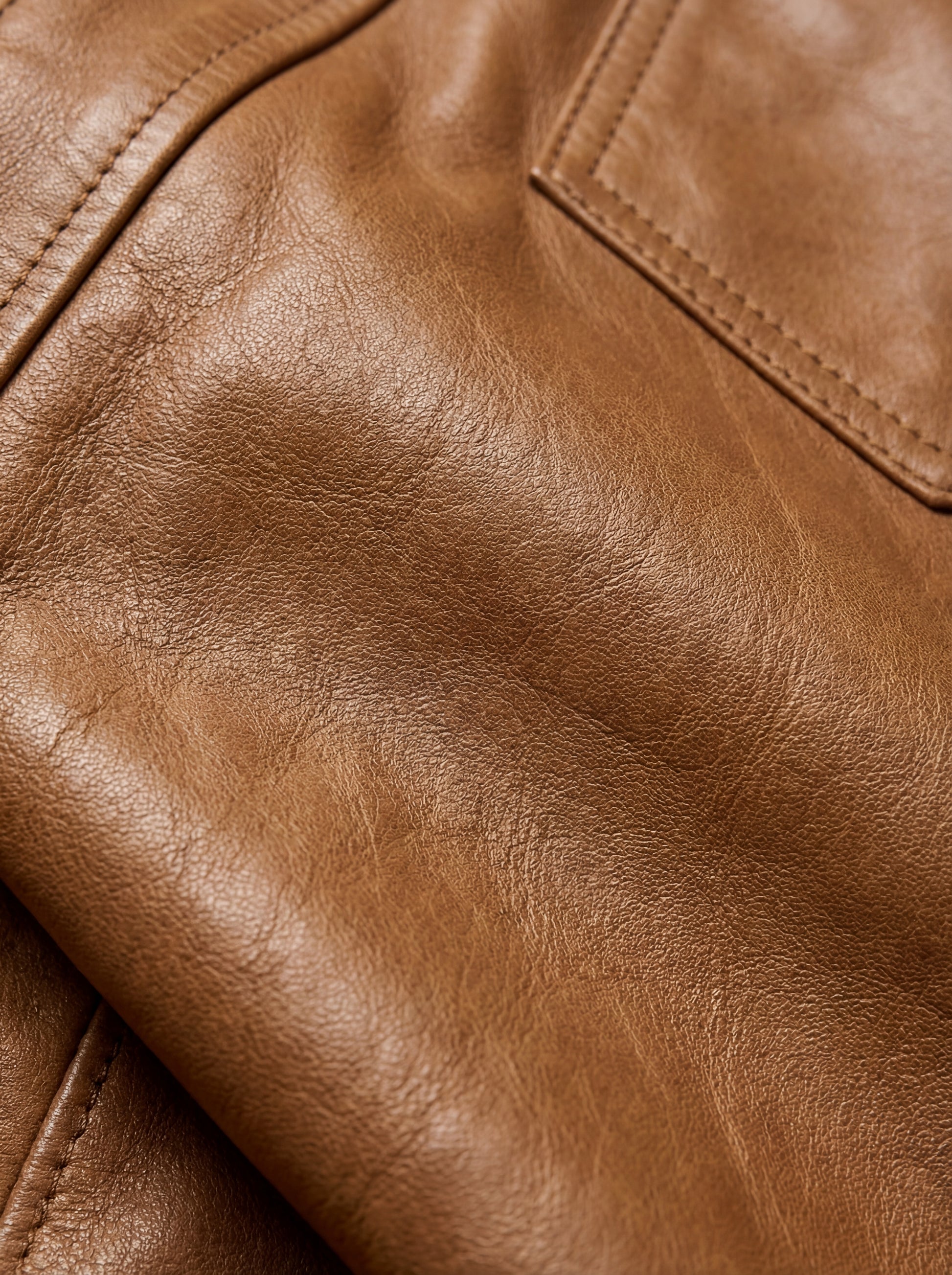 Macro shot of grained tan leather texture and silver snap button detail on western shirt. The Colton by Maverick Jacket.