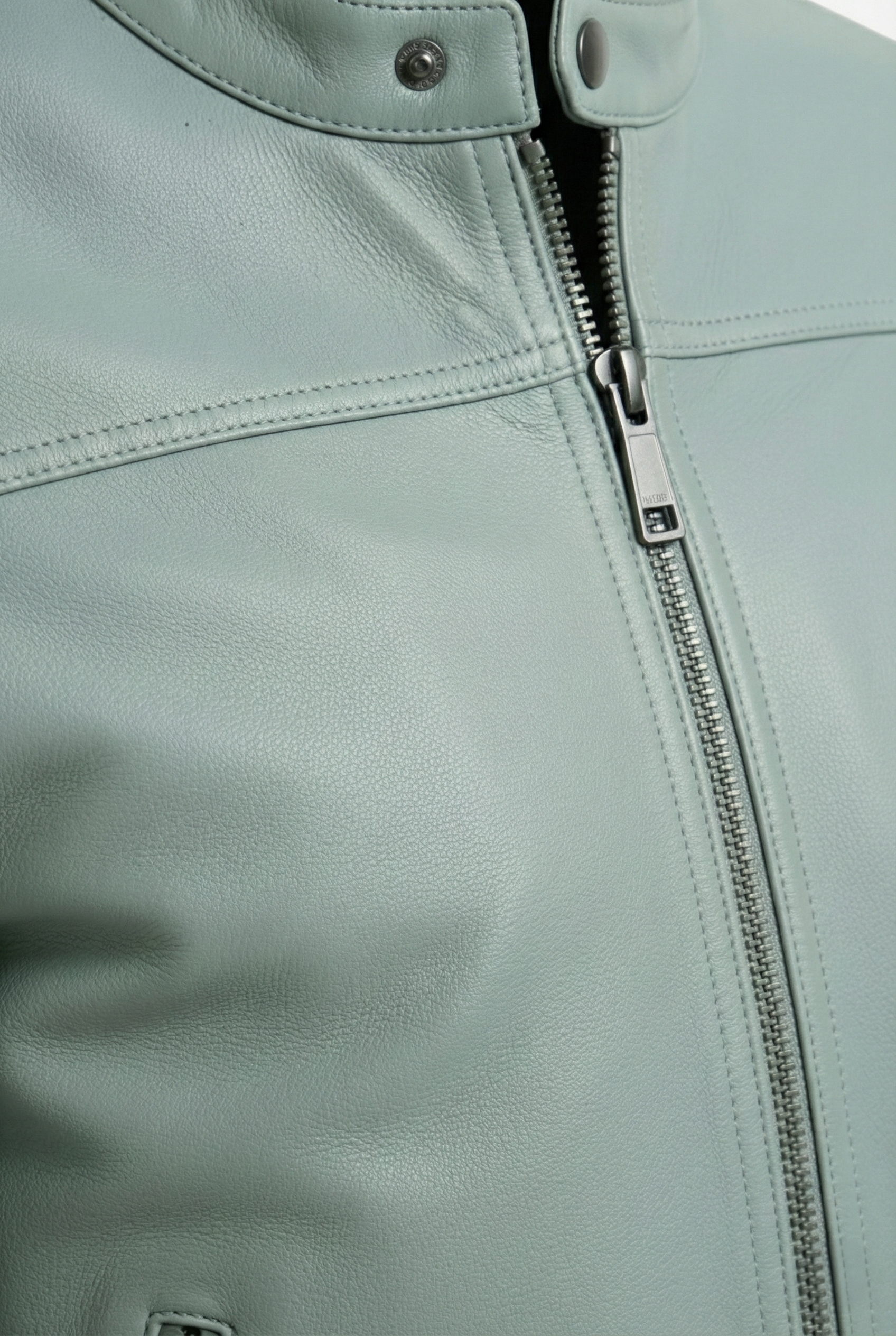 Macro shot of sage green pebbled leather grain and gunmetal zipper hardware on biker jacket. The Orion by Maverick Jacket.