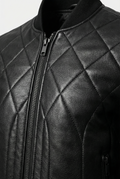 Macro shot of pebbled leather grain, gunmetal zipper hardware and diamond stitching on bomber jacket. The Vanta by Maverick Jacket.