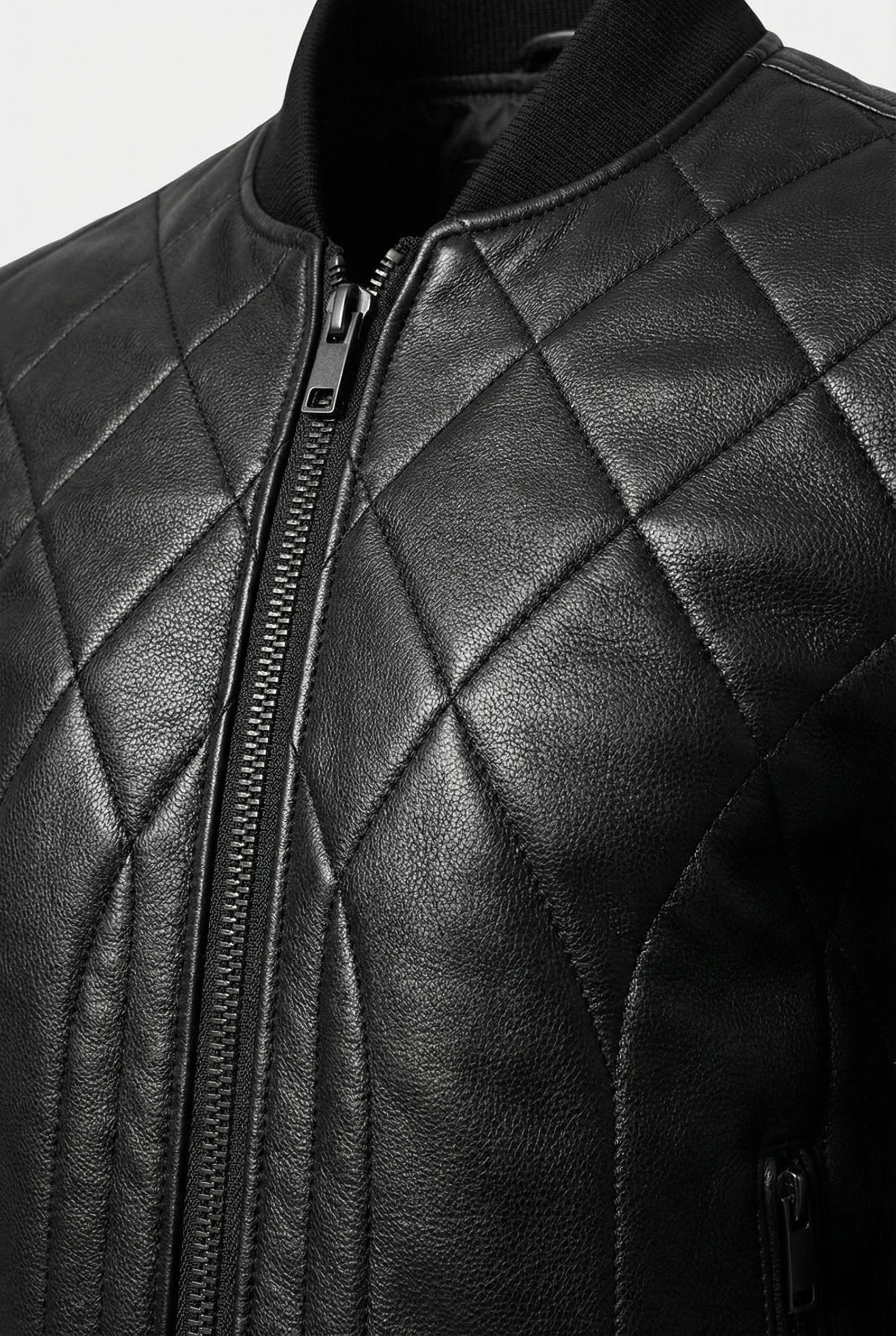 Macro shot of pebbled leather grain, gunmetal zipper hardware and diamond stitching on bomber jacket. The Vanta by Maverick Jacket.