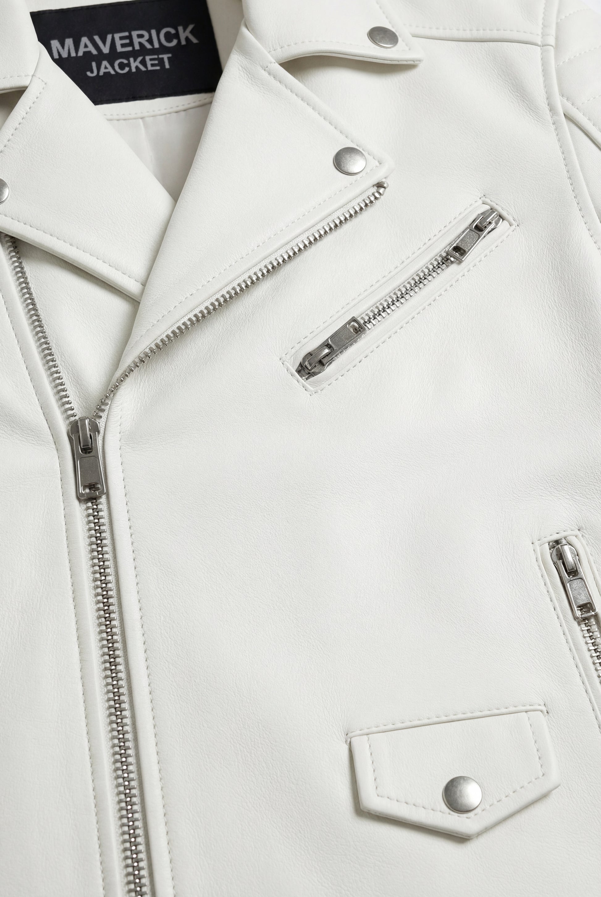 Macro shot of white pebbled leather grain texture and silver zipper hardware detail on biker jacket. The Lucent by Maverick Jacket.