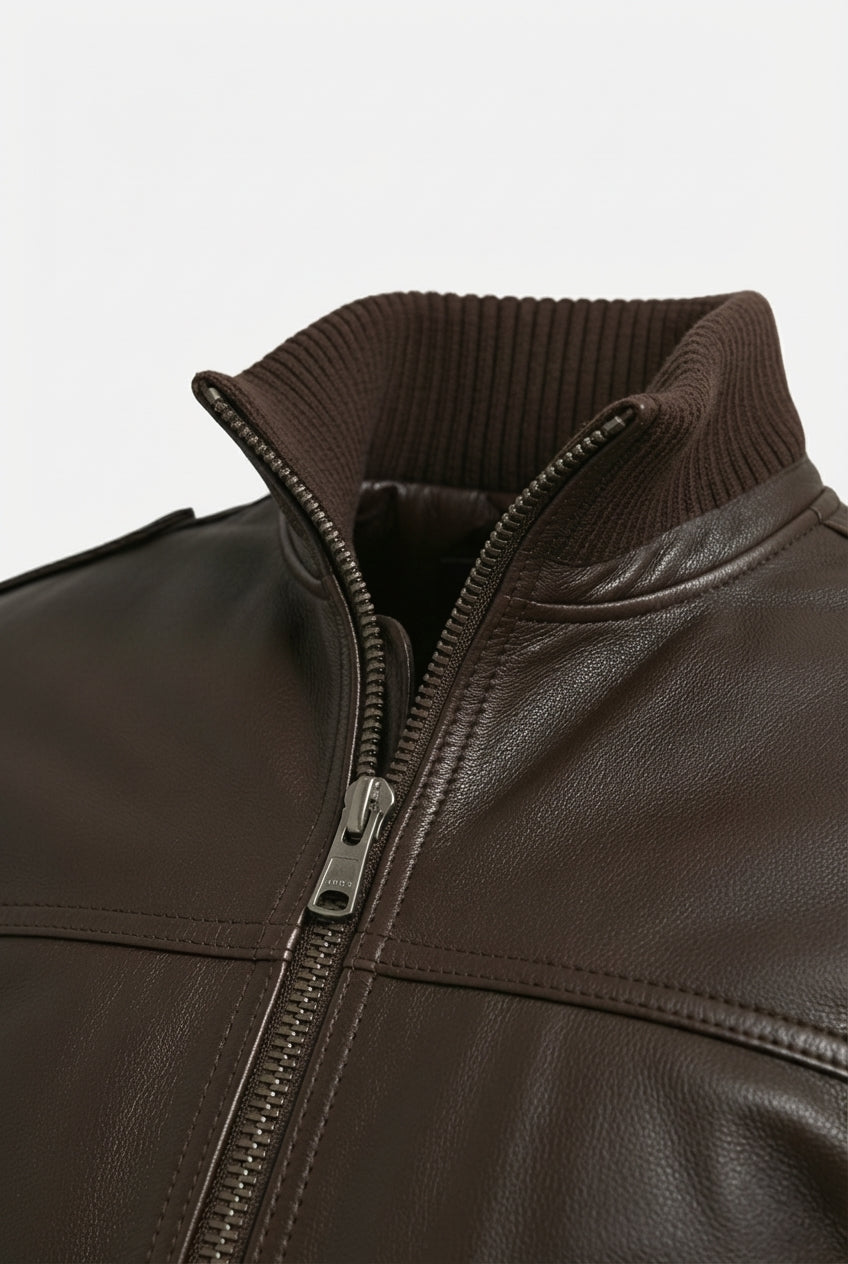 Macro shot of dark brown pebbled leather texture and ribbed knit collar detail on bomber jacket. The Alder by Maverick Jacket.