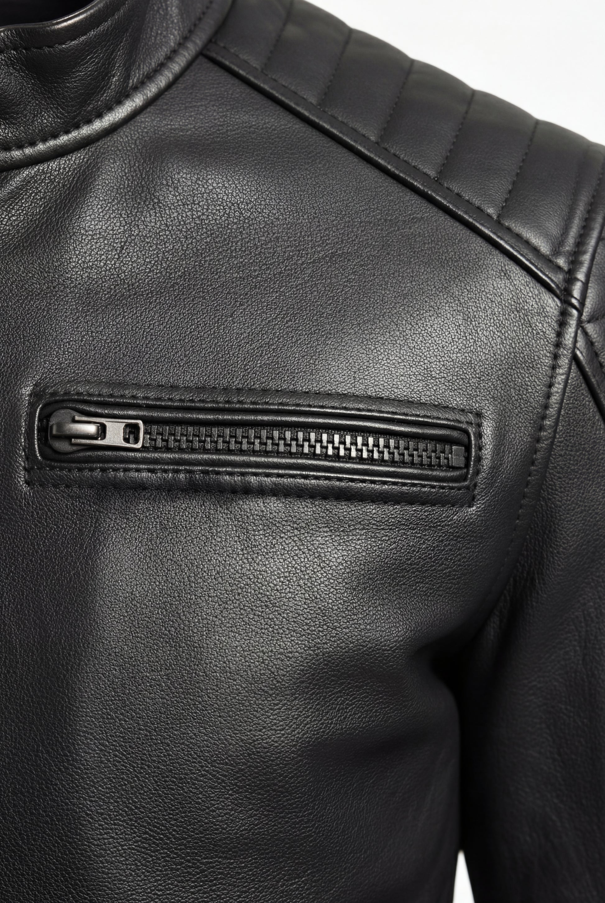 Macro shot of black leather grain texture and dark metal zipper pocket on moto jacket. The Axton by Maverick Jacket.