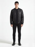 Male model wearing Maverick Nero quilted bomber jacket, slim fit, styled with black t-shirt and black skinny jeans. Maverick Jacket.