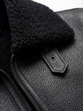 Macro shot of pebbled black leather texture and collar buckle hardware on jacket. The Zane by Maverick Jacket.