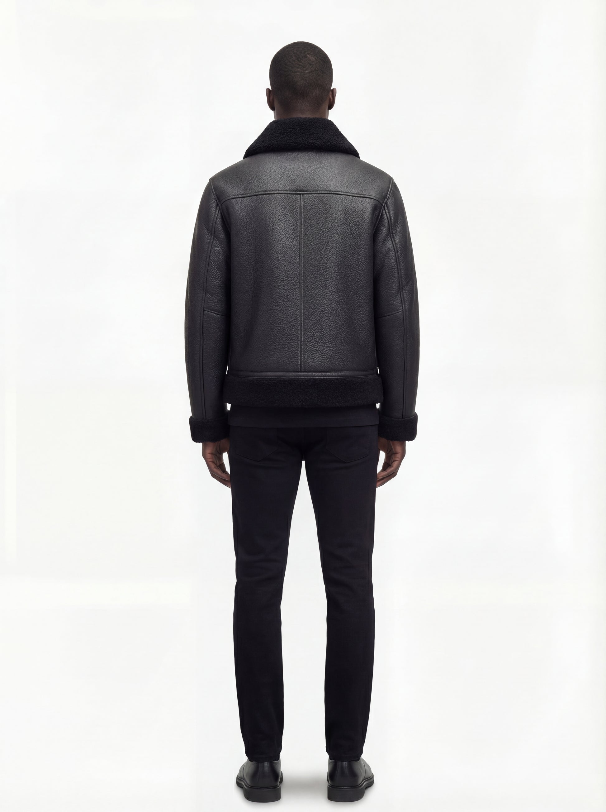 Rear view of male model wearing Maverick Zane shearling jacket showing structured shoulder fit and shearling-trimmed hem. Maverick Jacket.