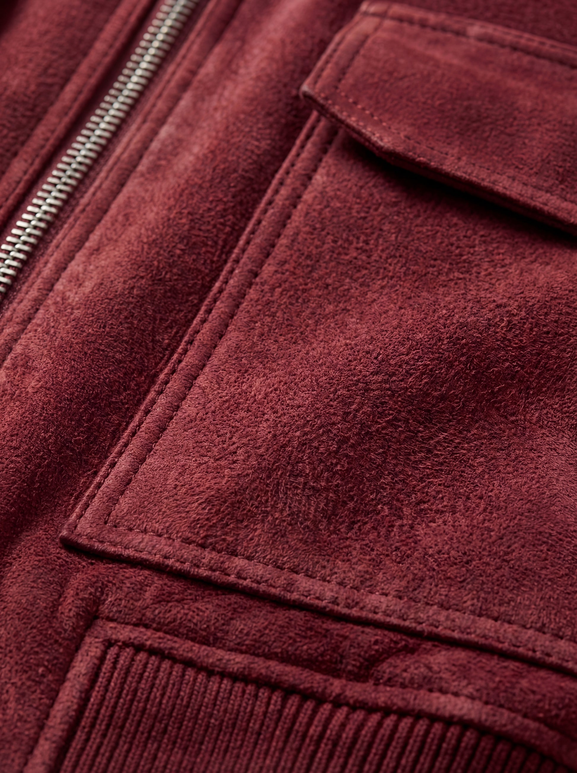 Macro shot of soft red suede texture and pocket stitching detail on bomber jacket. The Rory by Maverick Jacket.