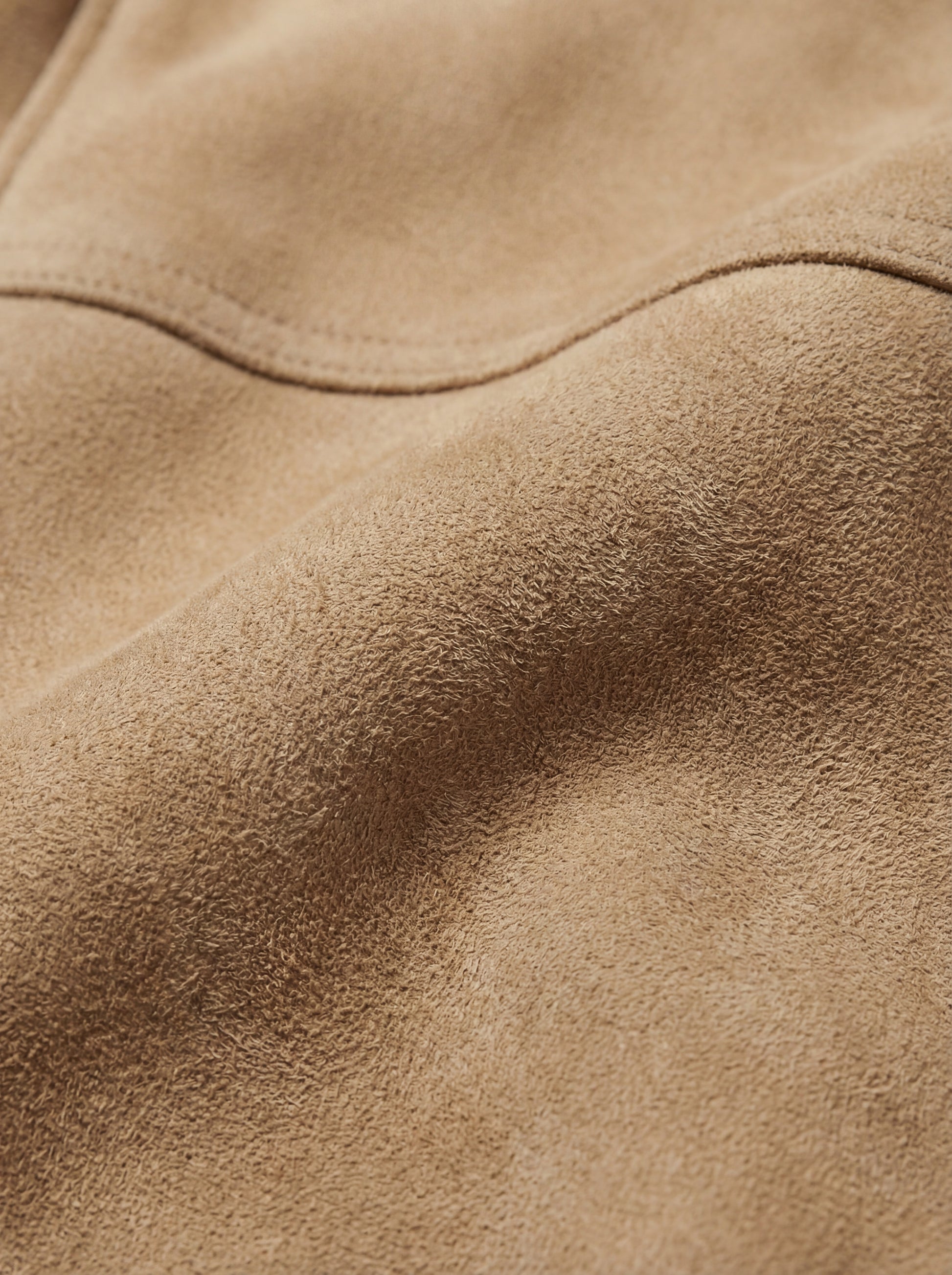 Macro shot of soft suede leather texture and tonal stitching details on bomber jacket. The Finn by Maverick Jacket.
