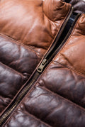 Macro shot of smooth leather texture and metal zipper hardware on two-tone puffer vest. The Caleb by Maverick Jacket.