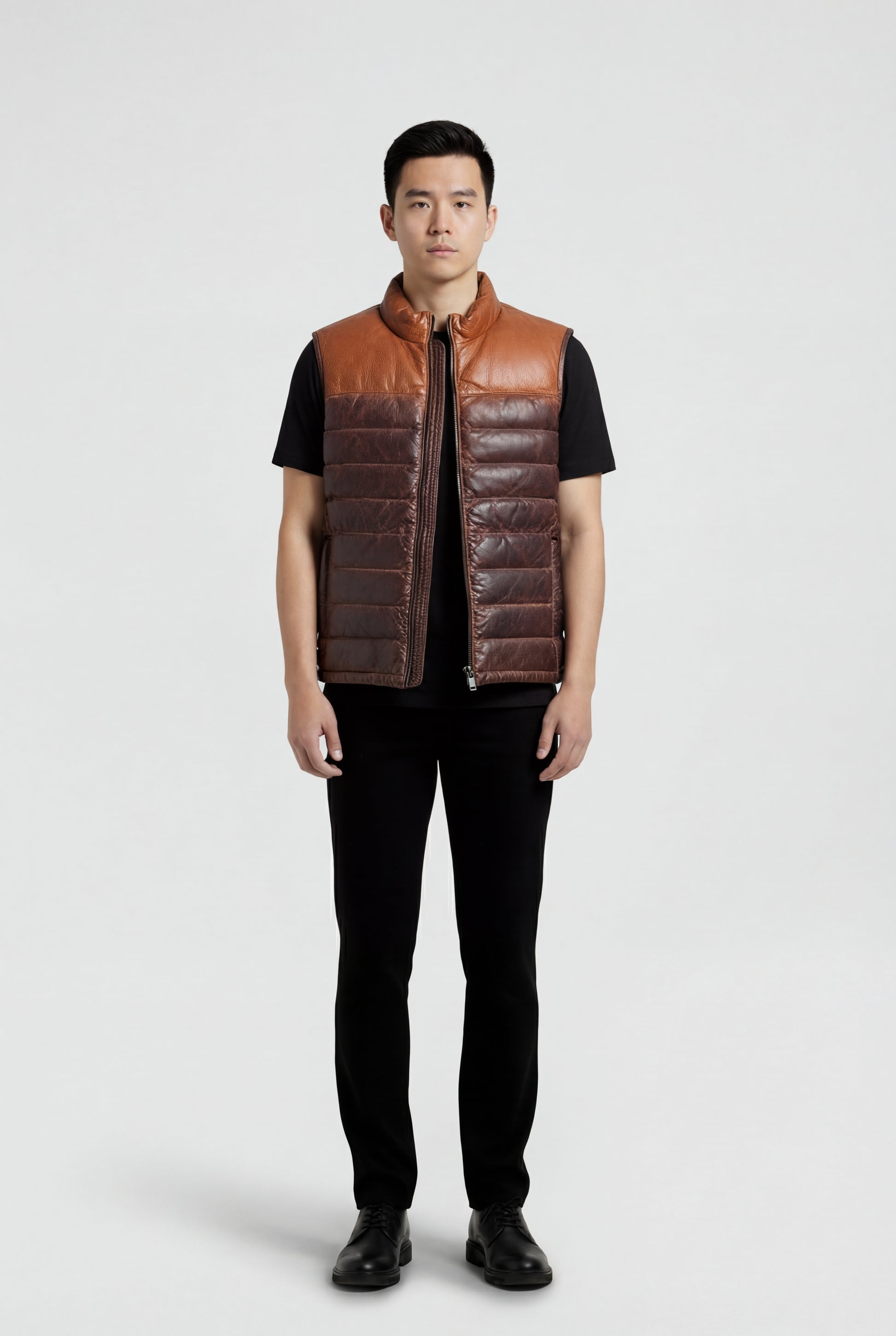 Male model wearing Maverick Caleb two-tone leather puffer vest, regular fit, styled over a grey hoodie with black denim jeans. Maverick Jacket.