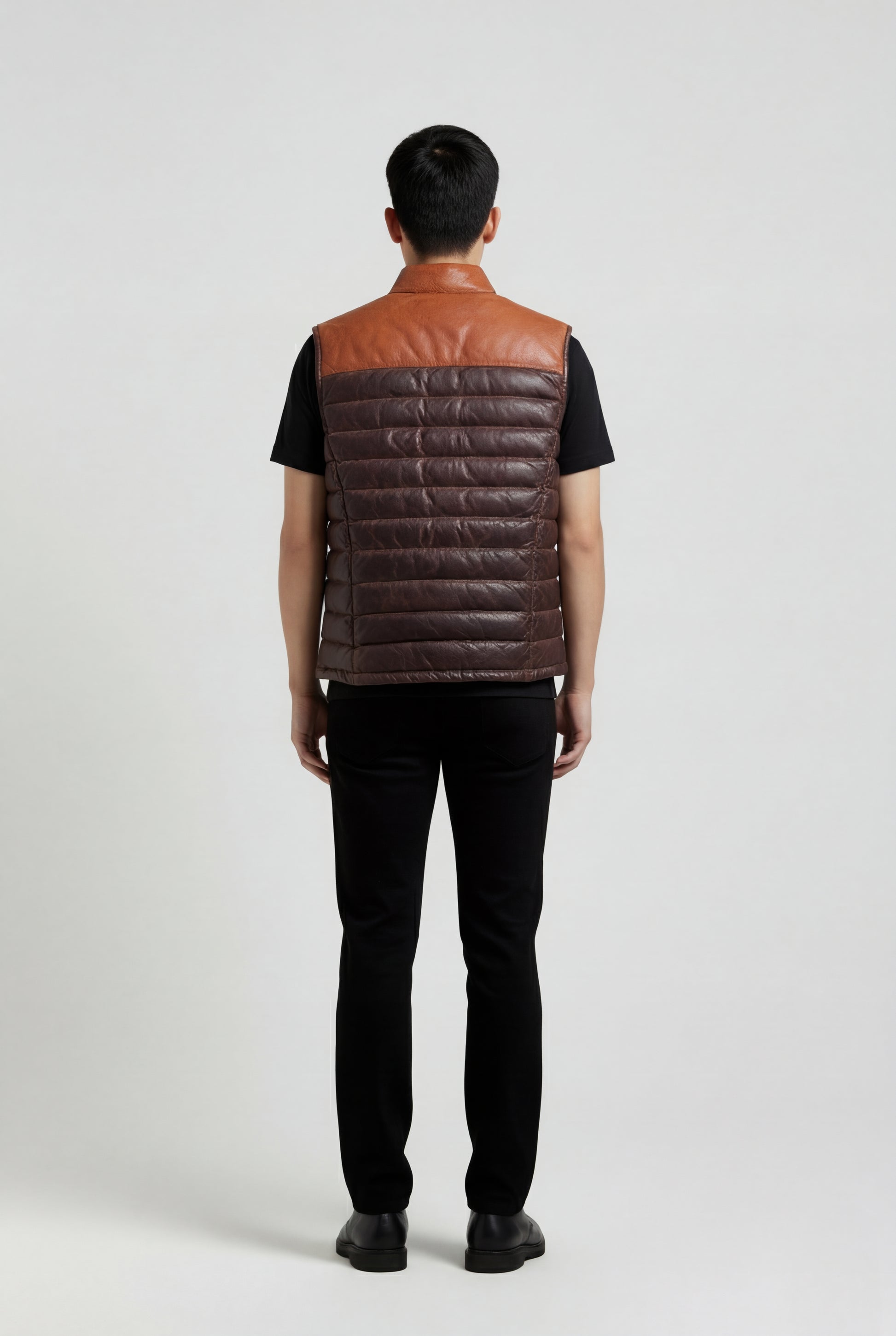Rear view of male model wearing Maverick Caleb leather puffer vest showing structured shoulder yoke and clean back styling. Maverick Jacket.