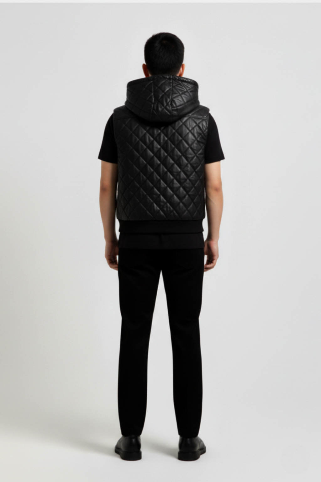 Rear view of male model wearing Maverick Reid quilted leather hooded vest showing broad shoulder fit and hood drape styling. Maverick Jacket.