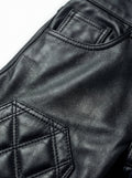 Macro shot of black pebbled leather texture and diamond quilting stitch detail on moto pants. The Jett by Maverick Jacket.