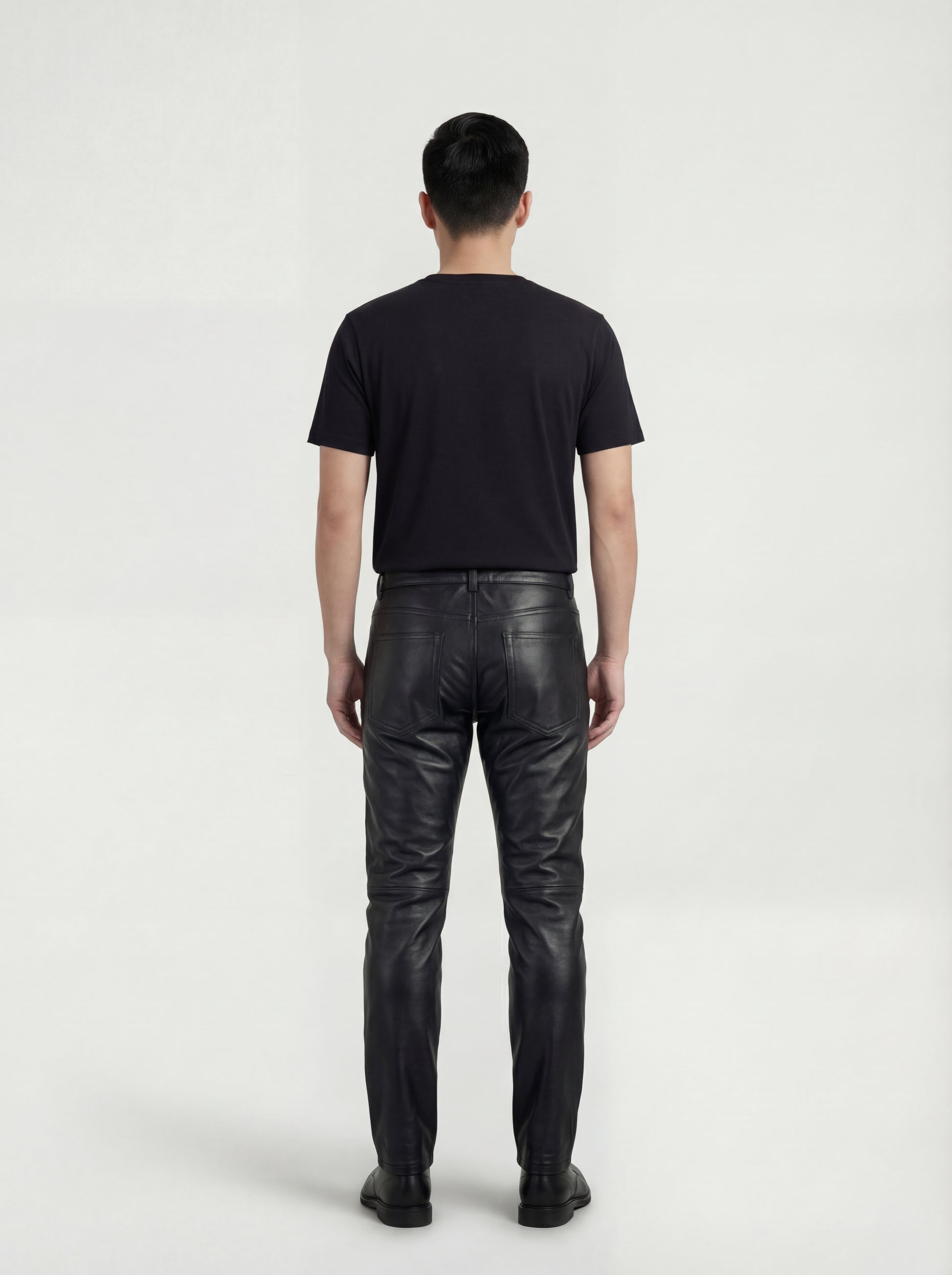 Rear view of male model wearing Maverick Jett quilted leather moto pants showing fitted seat silhouette and straight leg cut. Maverick Jacket.