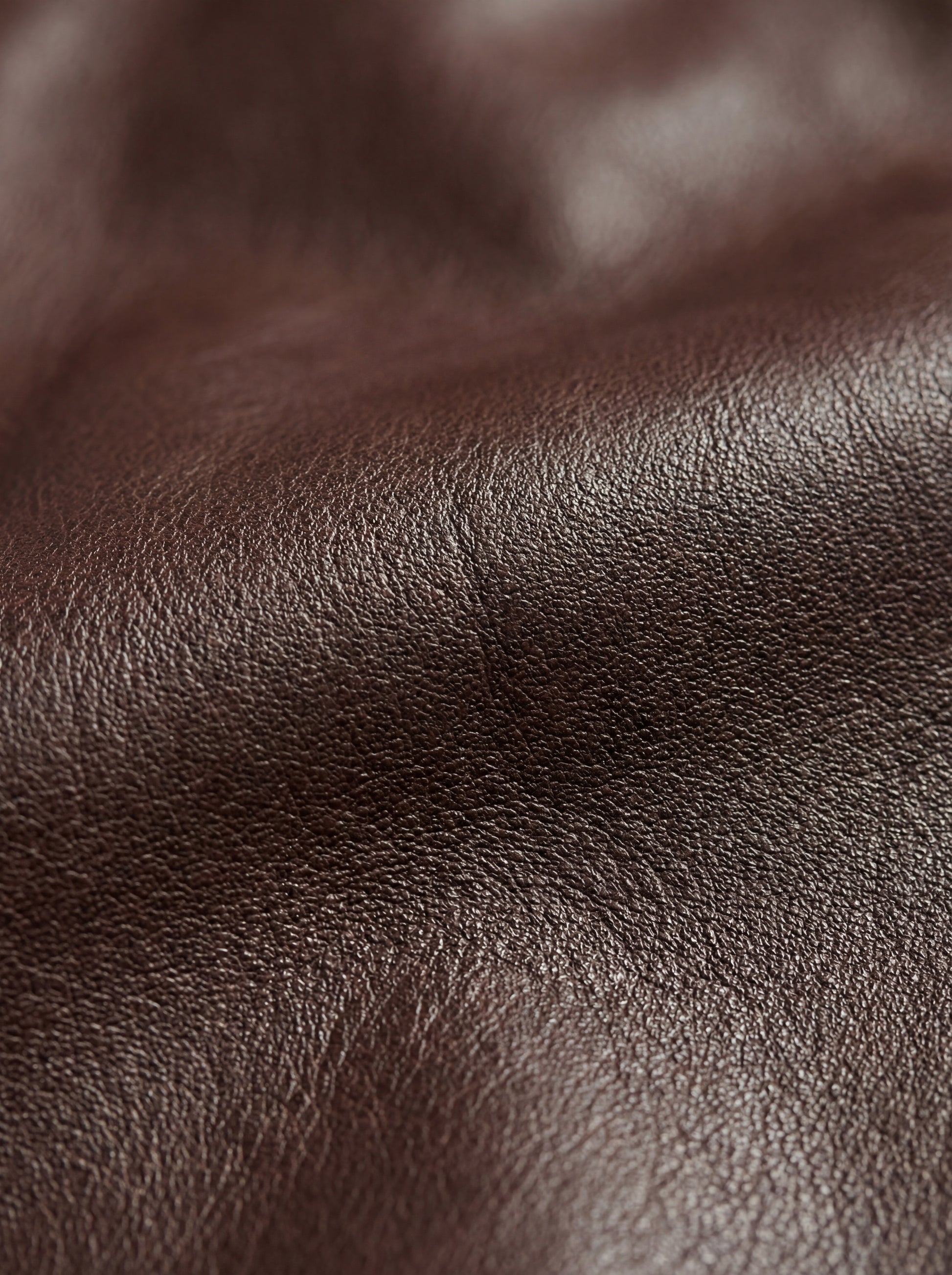 Macro shot of grained black leather texture and chest flap pocket stitching on zip-front shirt. The Elliot by Maverick Jacket.