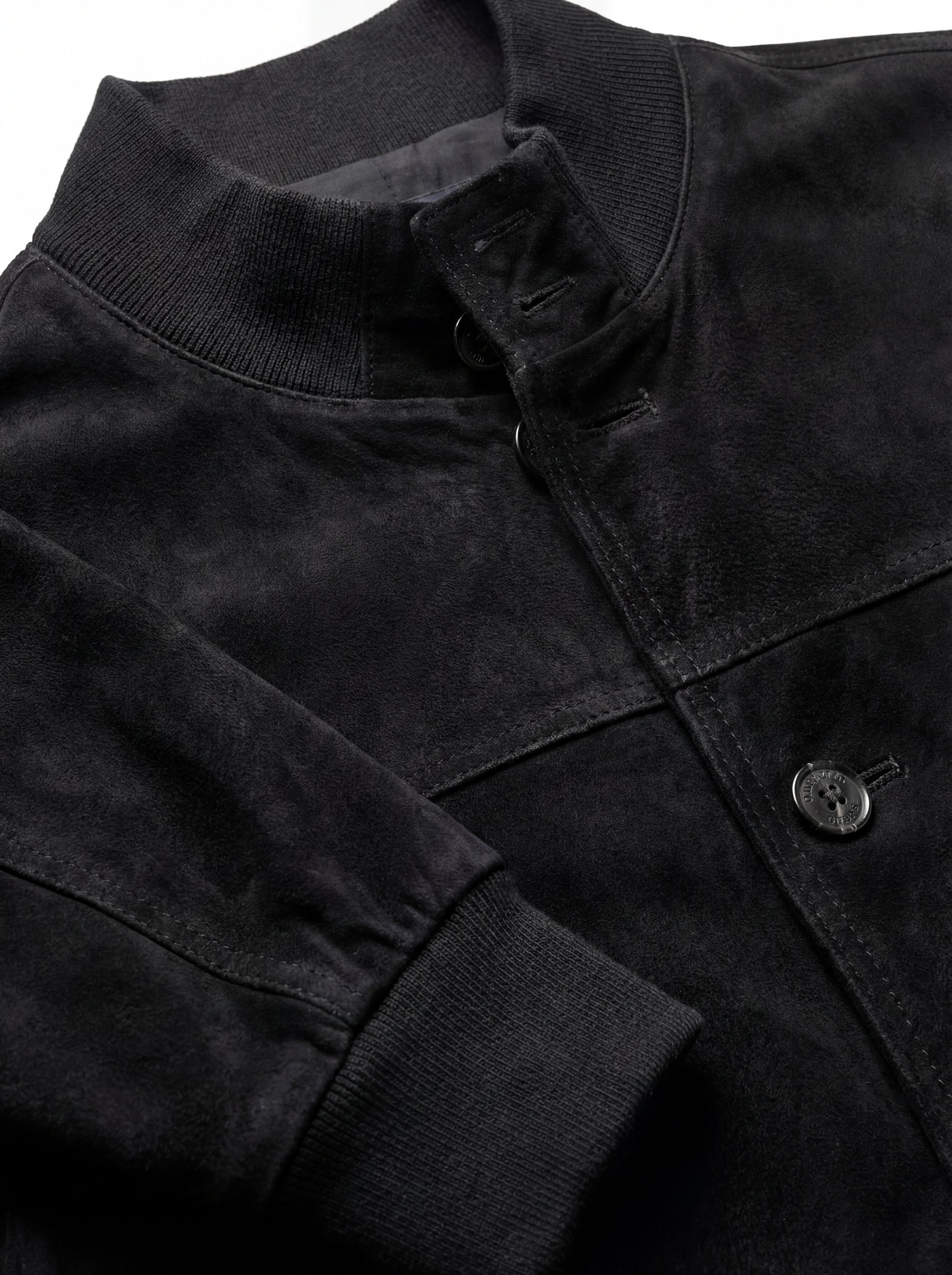 Macro shot of soft black suede texture and metal zipper hardware on bomber jacket. The Soren by Maverick Jacket.