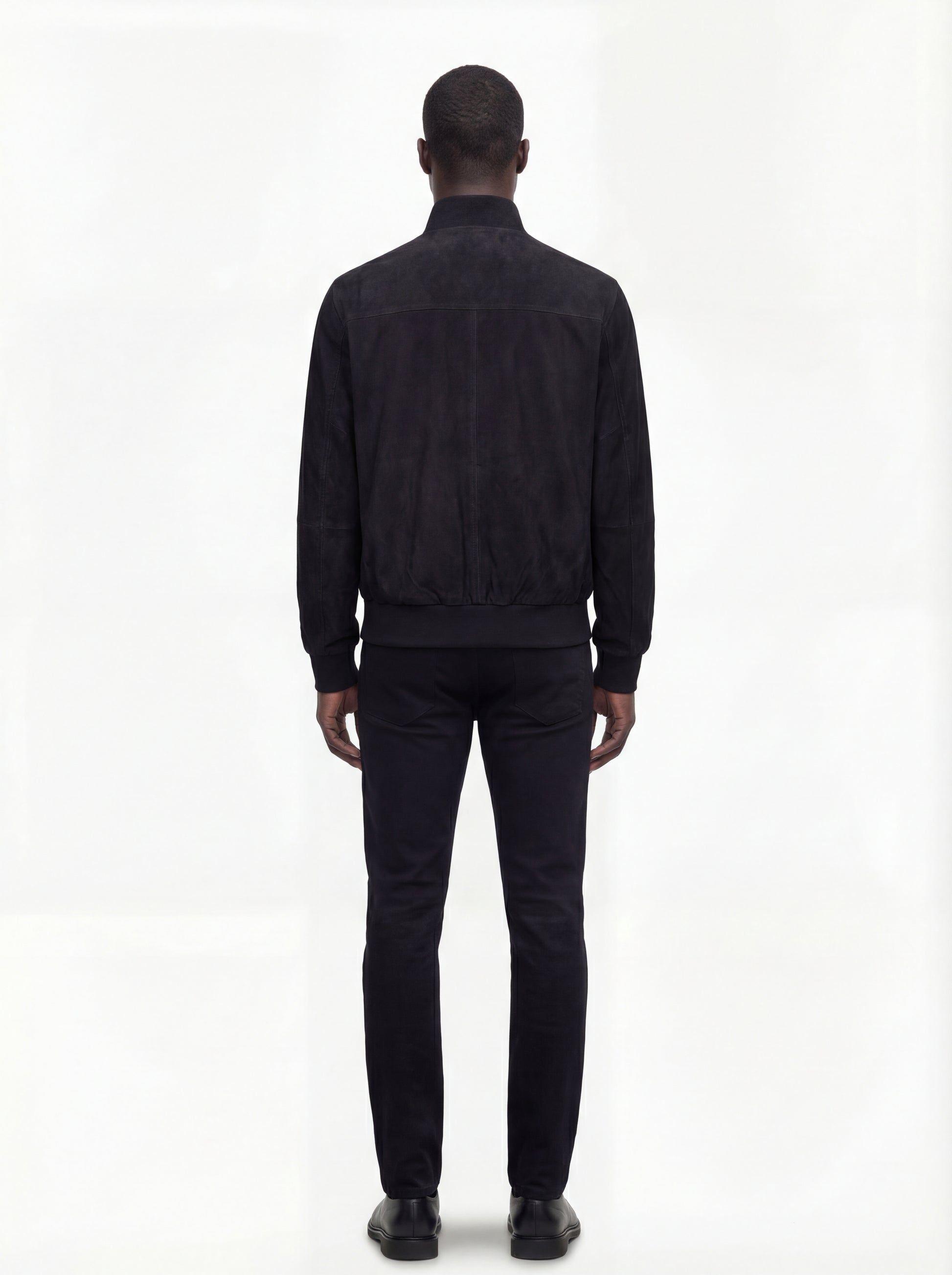 Rear view of male model wearing Maverick Soren suede bomber jacket showing broad shoulder fit and ribbed waist styling. Maverick Jacket.