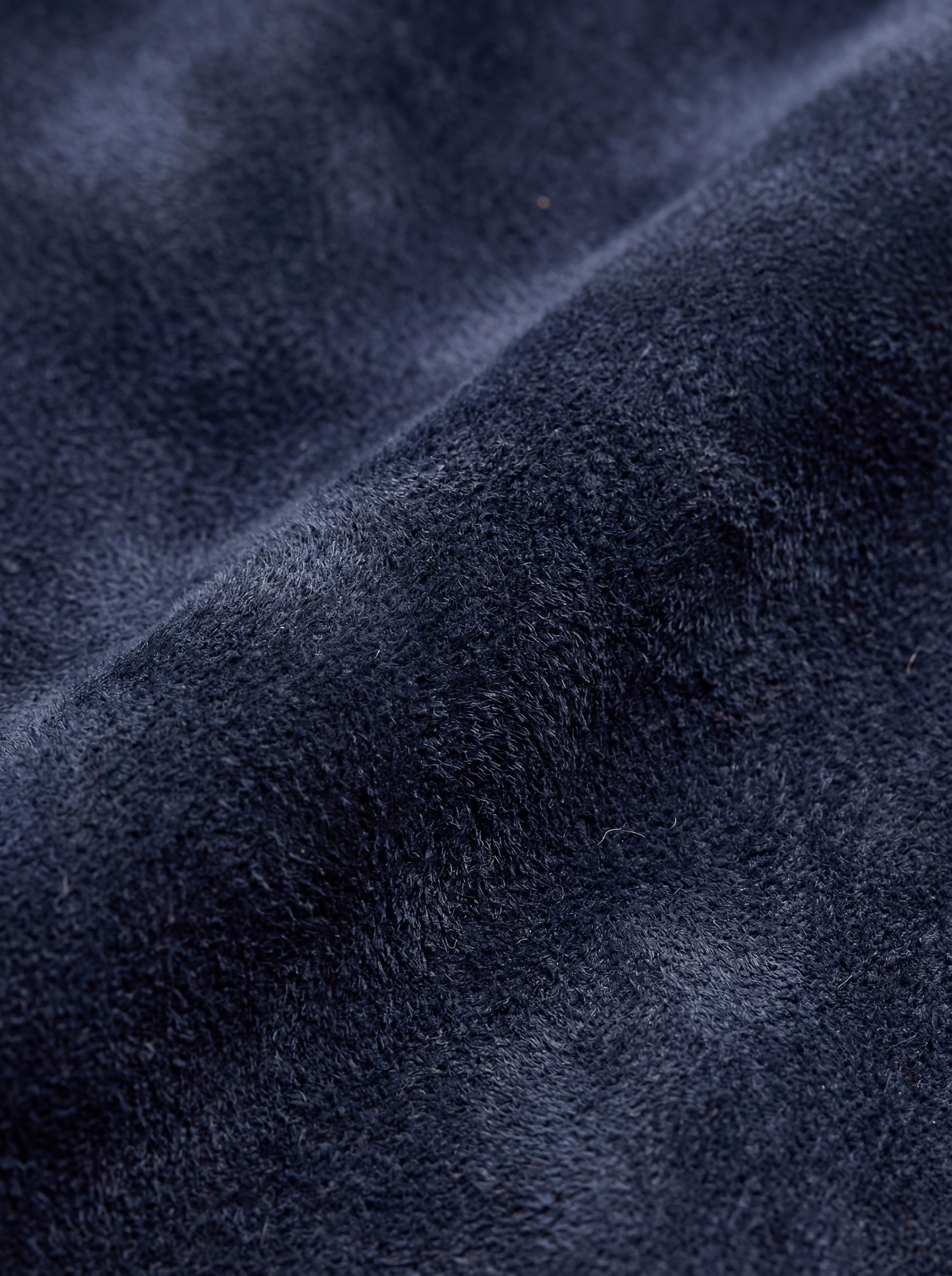 Macro shot of soft navy suede texture and silver hardware detail on trucker jacket. The August by Maverick Jacket.