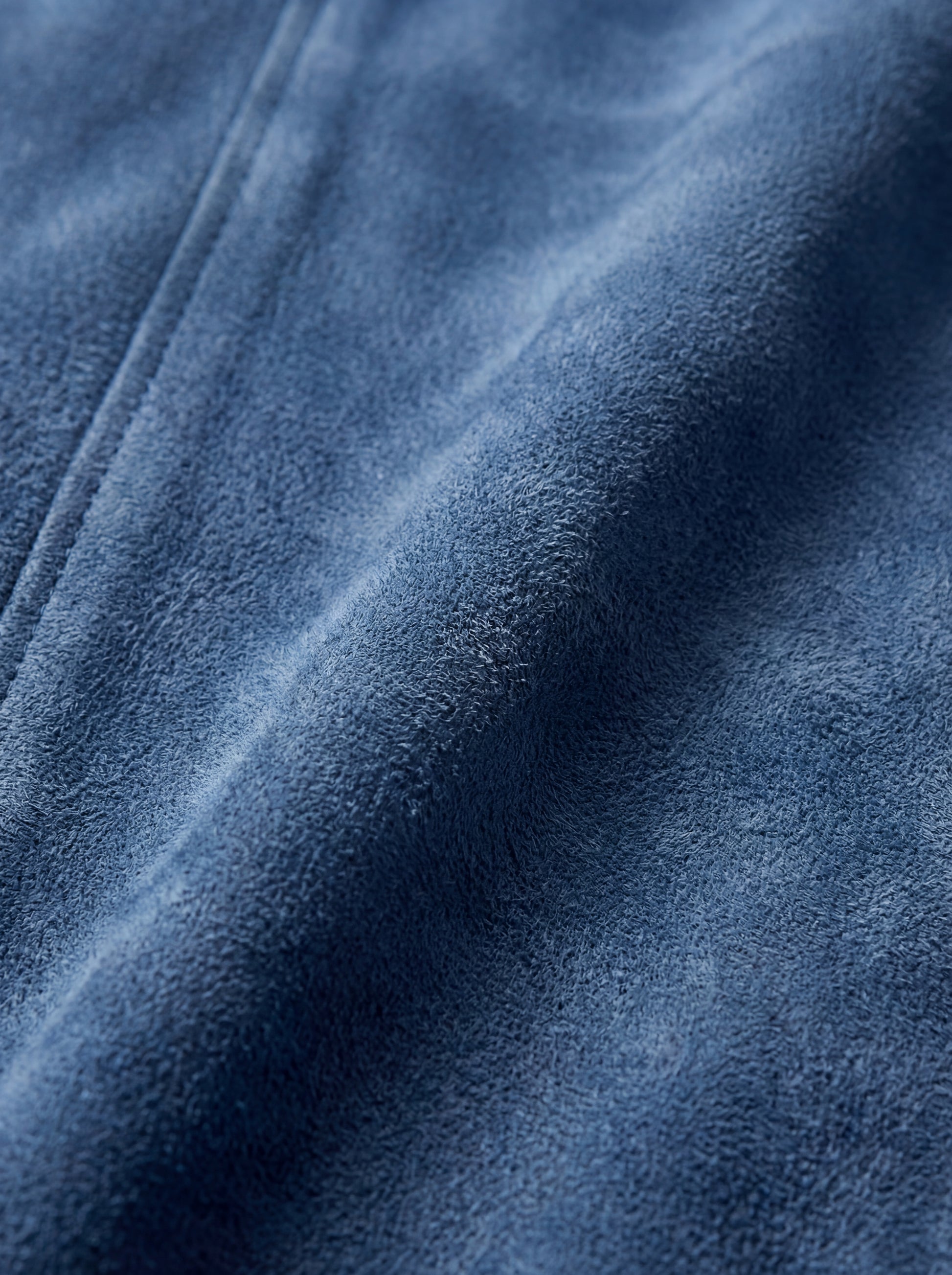Macro shot of soft blue suede texture and metal zipper hardware on bomber jacket. The Jude by Maverick Jacket.