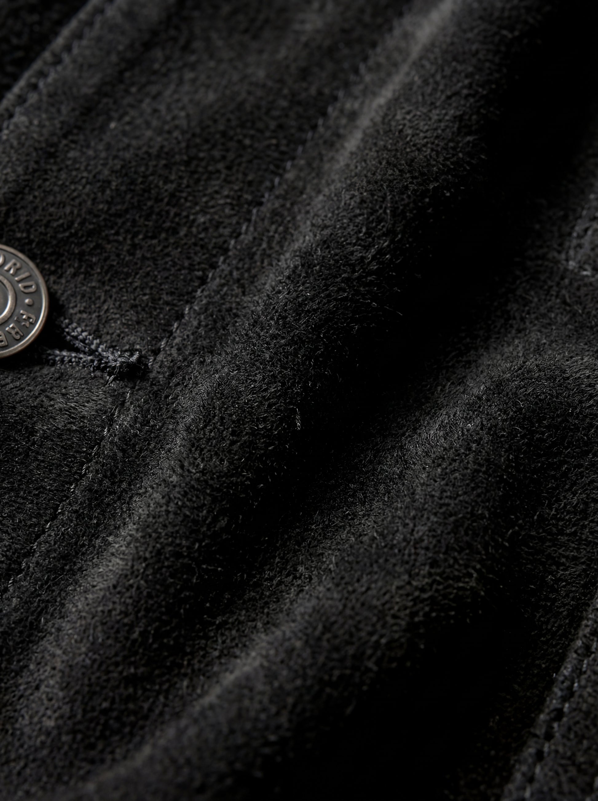 Macro shot of soft black suede texture and silver hardware detail on trucker jacket. The Lennon by Maverick Jacket.
