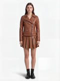 Female model wearing Maverick Stella leather biker jacket, slim fit, styled with Maverick Poppy tan pleated leather skirt. Maverick Jacket.