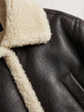 Macro shot of pebbled black leather grain and cream shearling fur texture on collar. The Thea by Maverick Jacket.