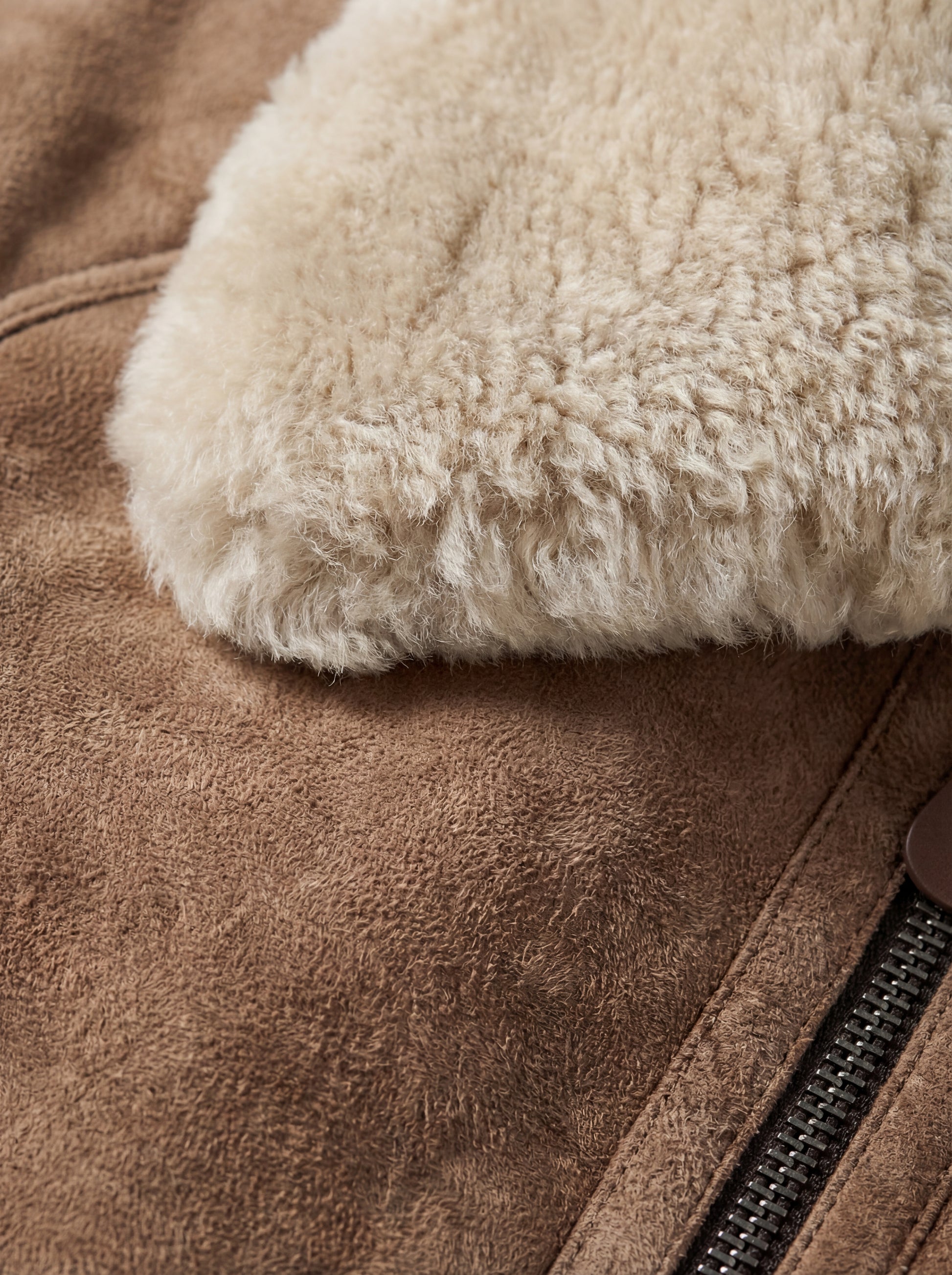 Macro shot of tan suede texture and cream shearling fur collar detail on aviator jacket. Maverick Anya.