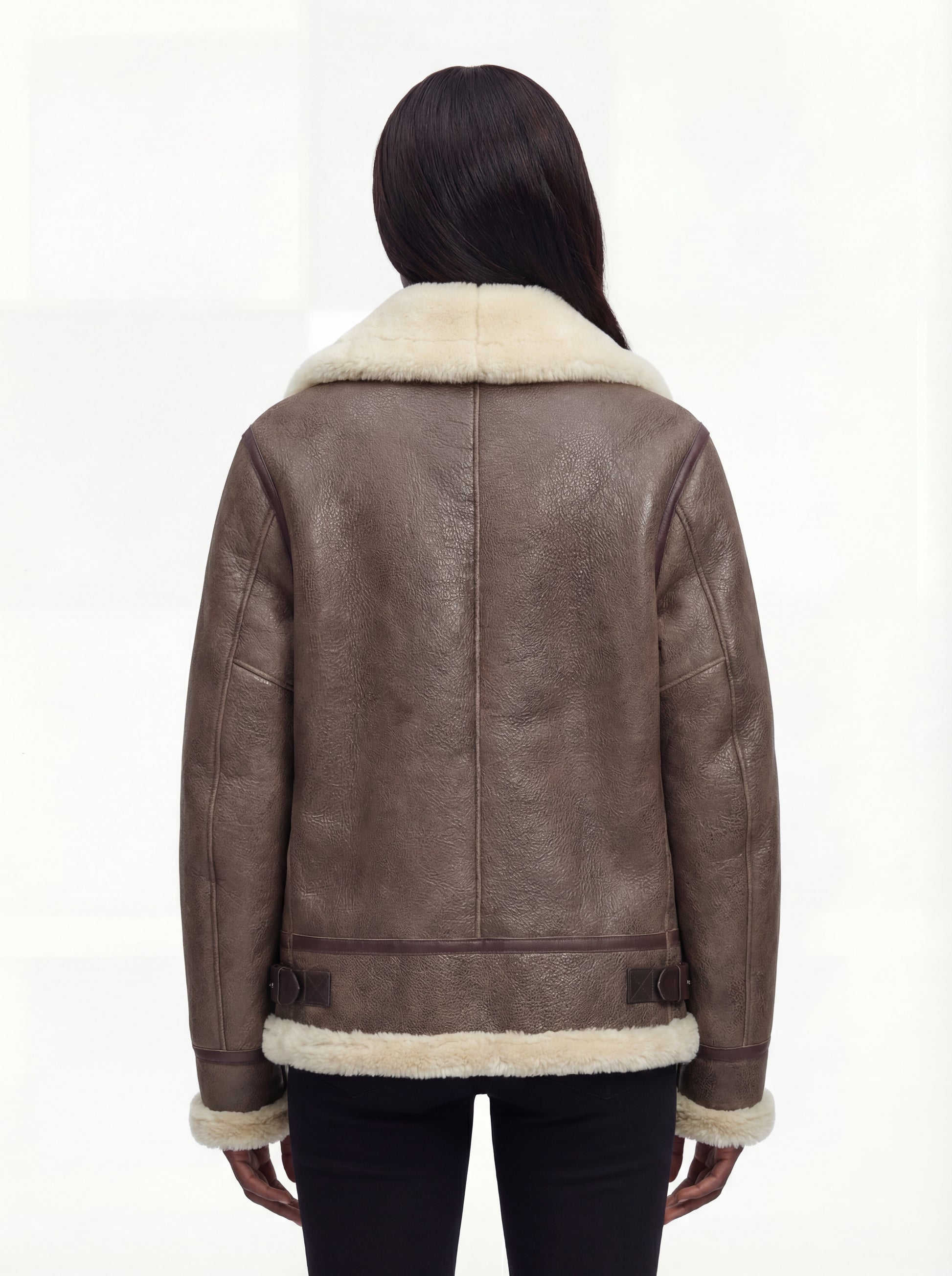 Rear view of female model wearing Maverick Paige shearling aviator jacket showing structured shoulders and shearling-trimmed hem. Maverick Paige.