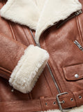Macro shot of pebbled tan leather texture and plush cream shearling cuff detail on biker jacket. Maverick Fallon.