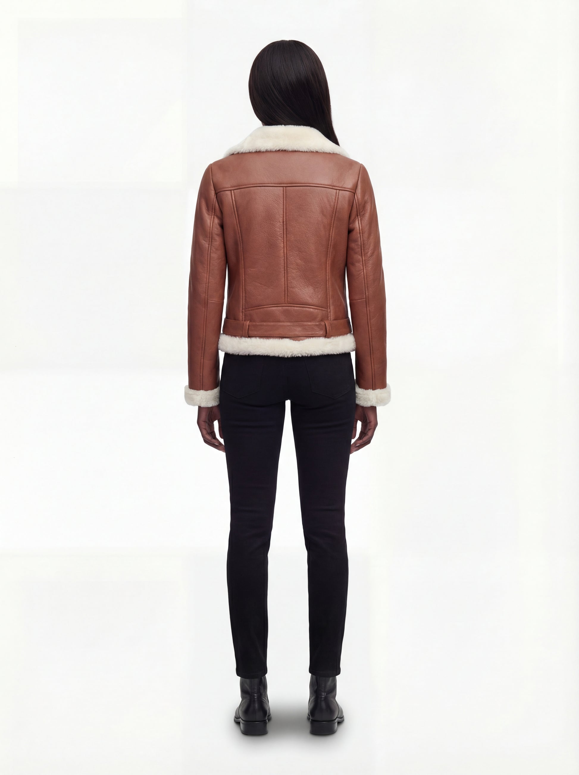 Rear view of female model wearing Maverick Fallon shearling biker jacket showing fitted shoulders and cream fur hem trim. Maverick Fallon.