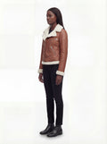 Side profile of Maverick Fallon shearling biker jacket showing thick fur cuffs and hip-length silhouette. Maverick Fallon.