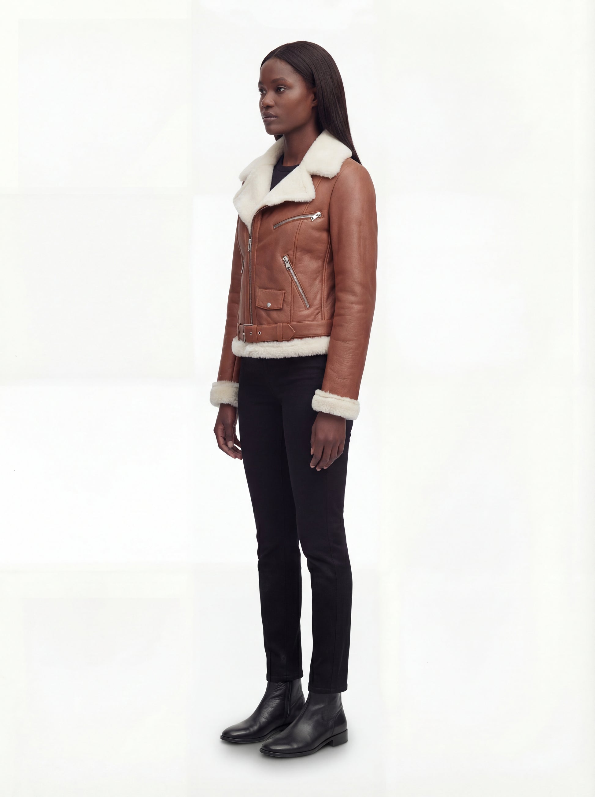 Side profile of Maverick Fallon shearling biker jacket showing thick fur cuffs and hip-length silhouette. Maverick Fallon.