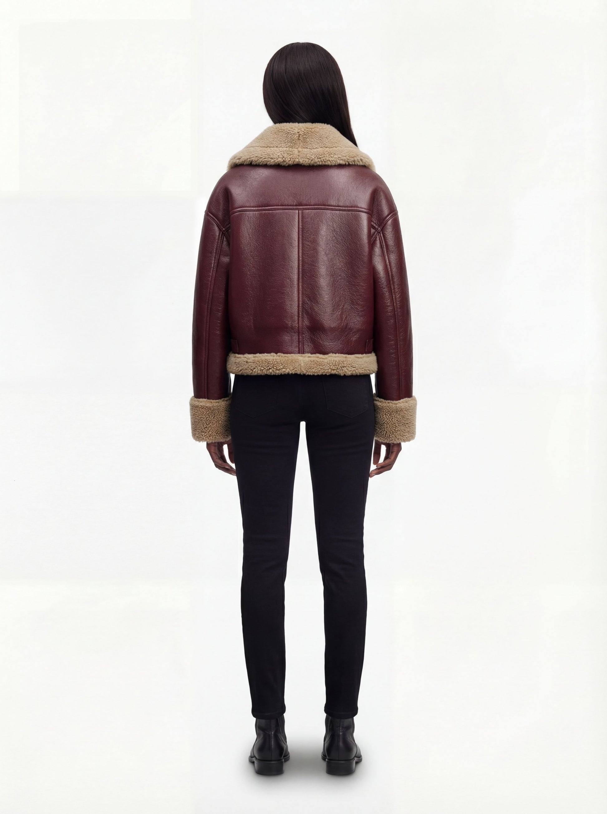 Rear view of female model wearing Maverick Faye shearling jacket showing relaxed shoulder drop and shearling-trimmed hem. Maverick Faye.