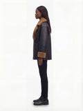 Side profile of Maverick Noa shearling jacket showing thick shearling cuffs and boxy hip-length silhouette. Maverick Noa.
