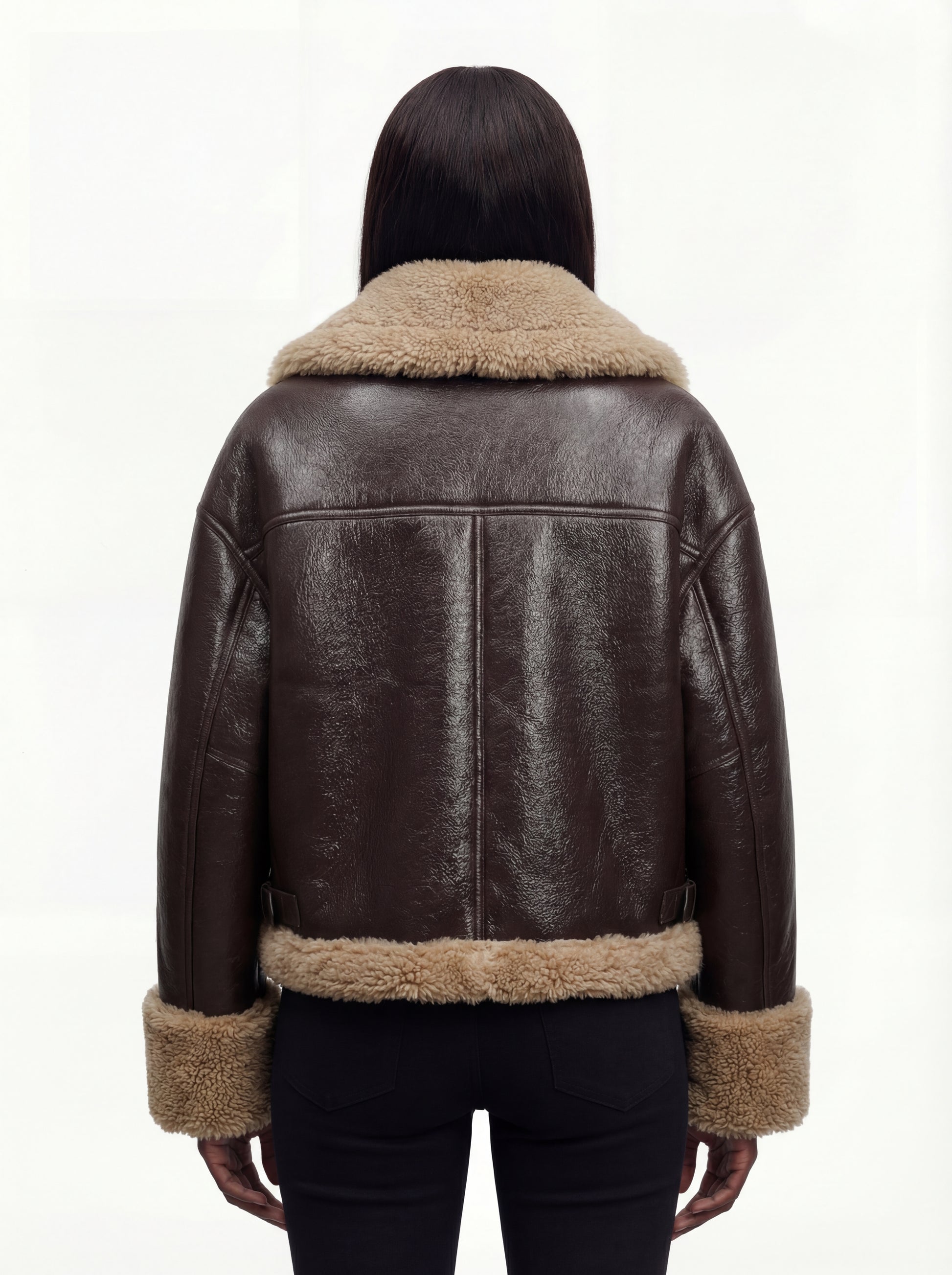 Rear view of female model wearing Maverick Faye shearling jacket showing relaxed shoulder drop and shearling-trimmed hem. Maverick Faye.