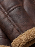Macro shot of distressed brown leather texture and beige shearling cuff detail on aviator jacket. Maverick Sierra.