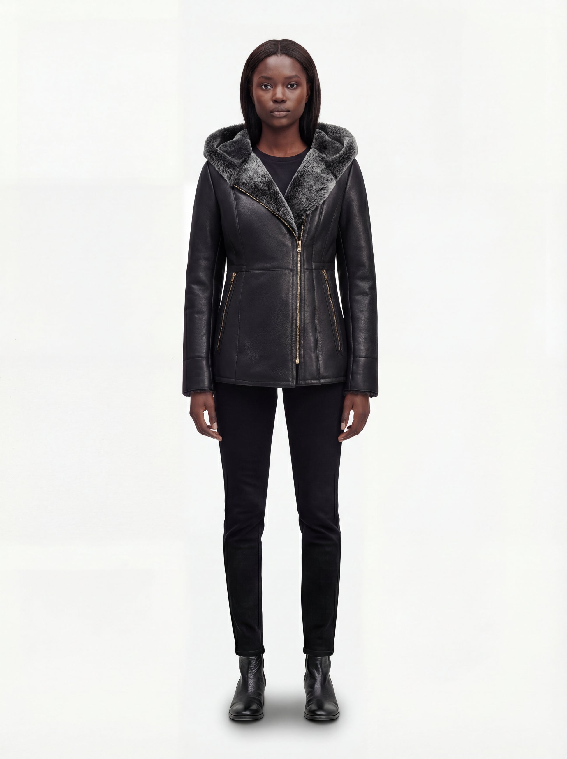 Female model wearing Maverick Genevieve hooded shearling coat, slim fit, styled over a knit sweater with skinny black jeans. Maverick Jacket.