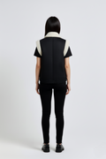 Rear view of female model wearing Maverick Elle shearling vest showing structured shoulder fit and straight back styling. Maverick Jacket.