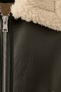 Macro shot of pebbled black leather texture and silver metal zipper hardware on shearling vest. The Clara by Maverick Jacket.
