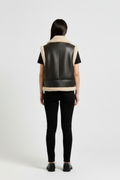 Rear view of female model wearing Maverick Clara shearling vest showing structured shoulder fit and straight hem styling. Maverick Jacket.