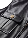 Macro shot of black leather grain texture and gold embossed button detail on utility vest. The Victoria by Maverick Jacket.