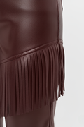 Macro shot of smooth burgundy leather texture and precision-cut fringe detailing on pants. The Stevie by Maverick Jacket.
