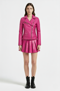 Female model wearing Maverick Poppy pleated leather skirt, mini fit, styled with fuchsia leather biker jacket and combat boots. Maverick Jacket.