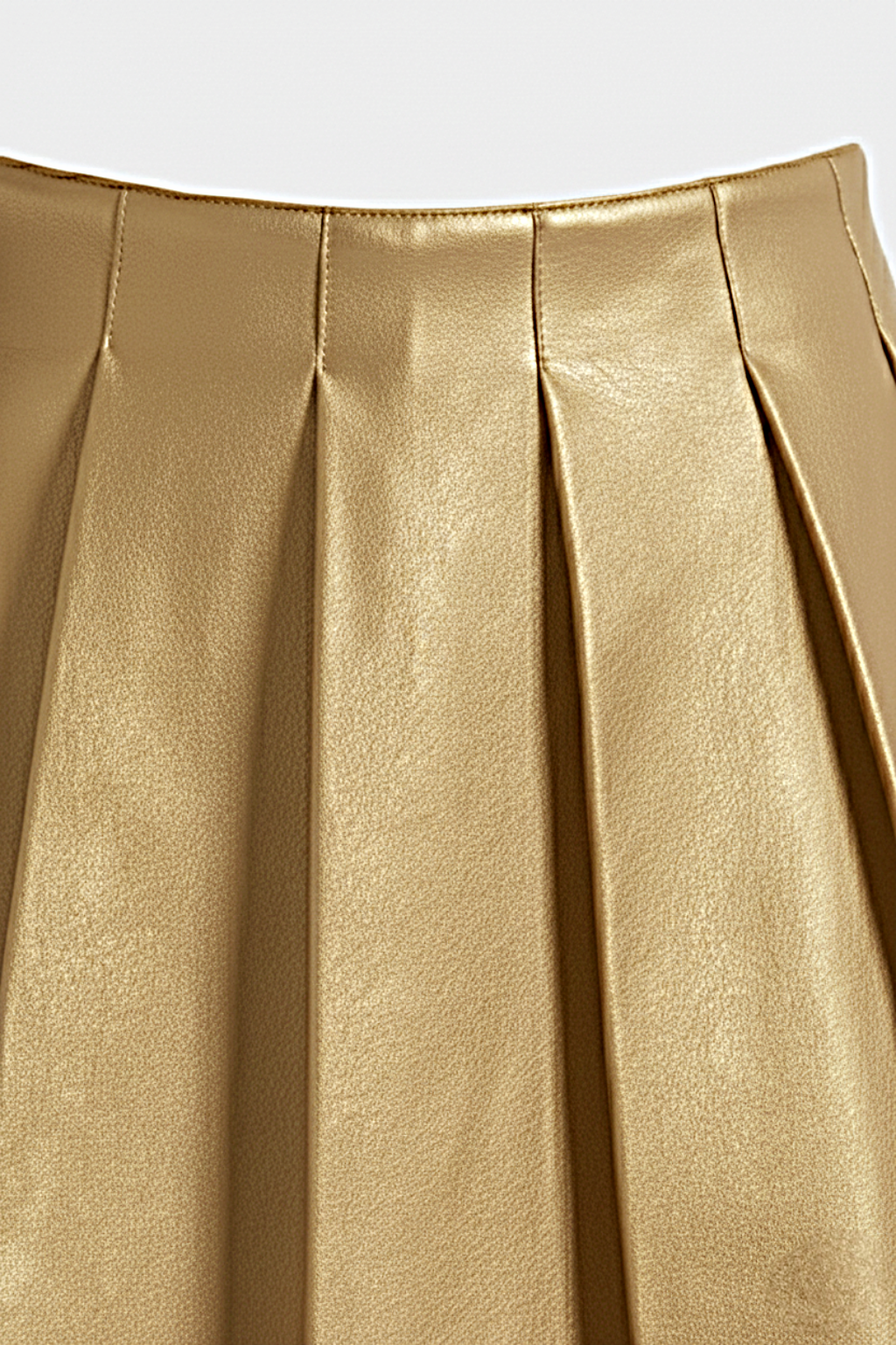 Macro shot of smooth gold leather grain and structured knife pleat detailing on skirt. The Poppy by Maverick Jacket.