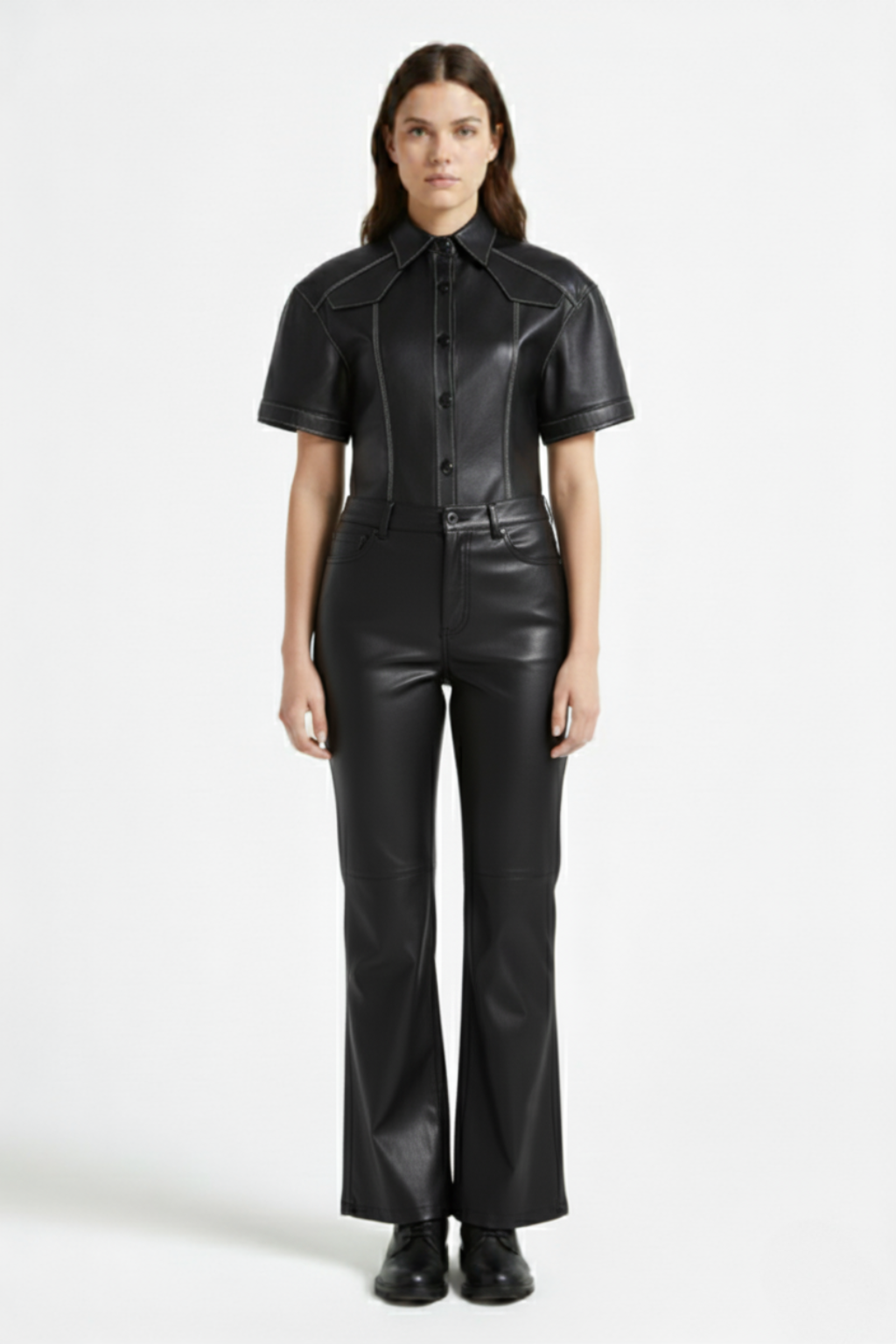 Female model wearing Maverick Bianca black leather flare pants, high-waisted fit, styled with matching black leather short-sleeve shirt and black leather boots. Maverick Jacket.