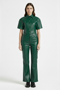 Female model wearing Maverick Bianca green leather flare pants, high-waisted fit, styled with matching green leather short-sleeve shirt and black leather boots. Maverick Jacket.
