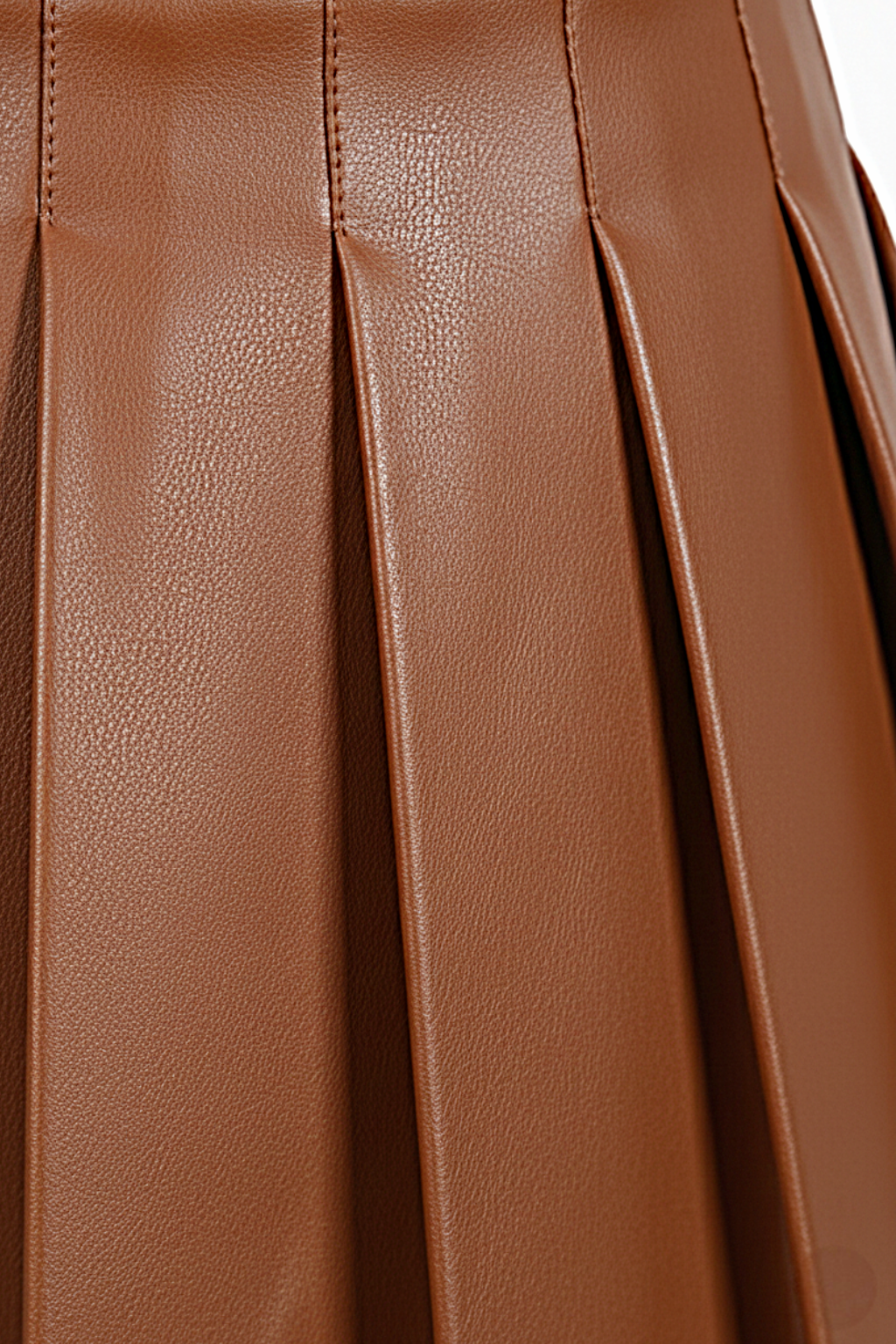 Macro shot of smooth tan leather grain and structured knife pleat detailing on skirt. The Poppy by Maverick Jacket.